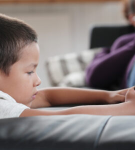 bambino con un dispositivo digitale e genitore sullo sfondo
