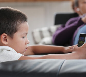 bambino con un dispositivo digitale e genitore sullo sfondo