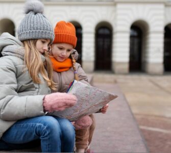 bambine che guardano una mappa durante un gioco di esplorazione in città