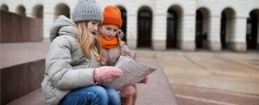 bambine che guardano una mappa durante un gioco di esplorazione in città
