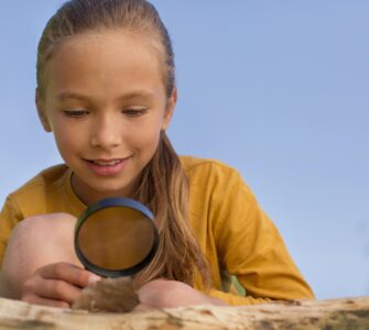 bambina che osserva una foglia con una lente nella mano